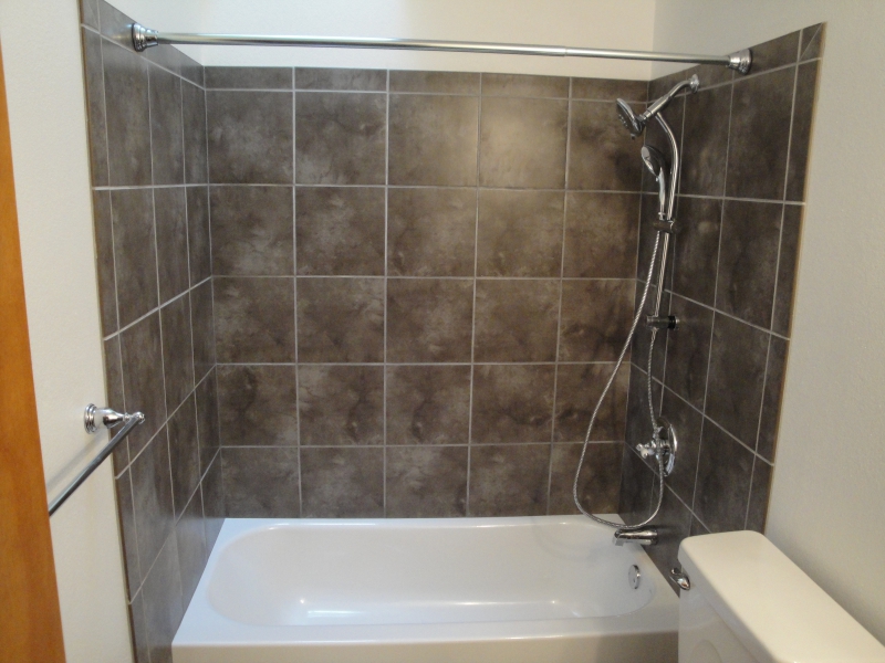 Grey tile tub enclosure with a white bathtub
