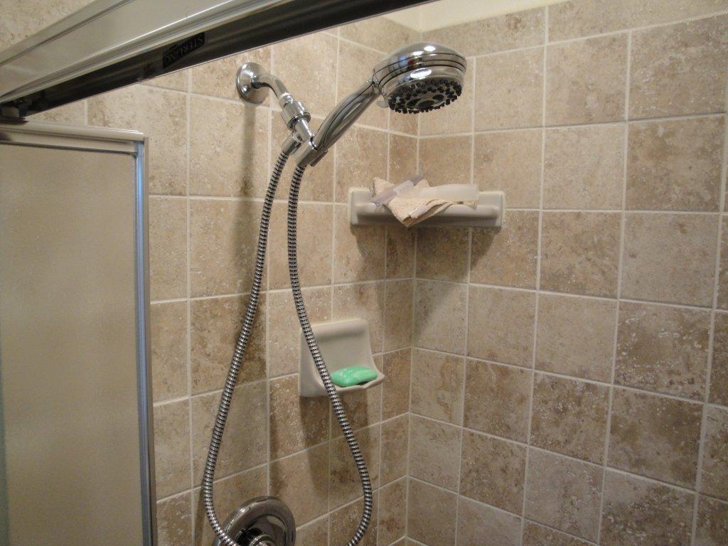 Porcelain tile shower with handheld shower head and corner shelves